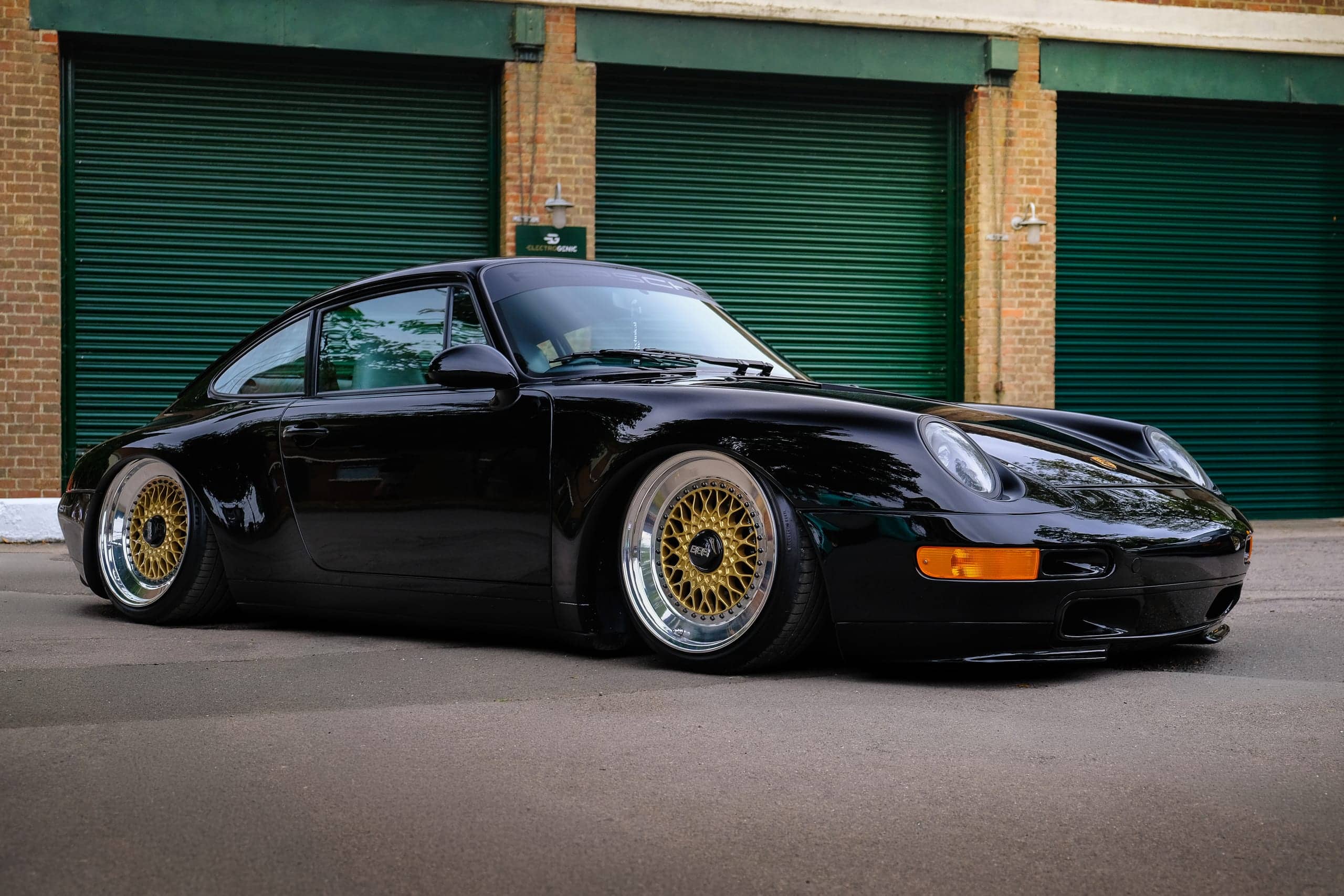 Modified black Porsche 911 parked outside a garage
