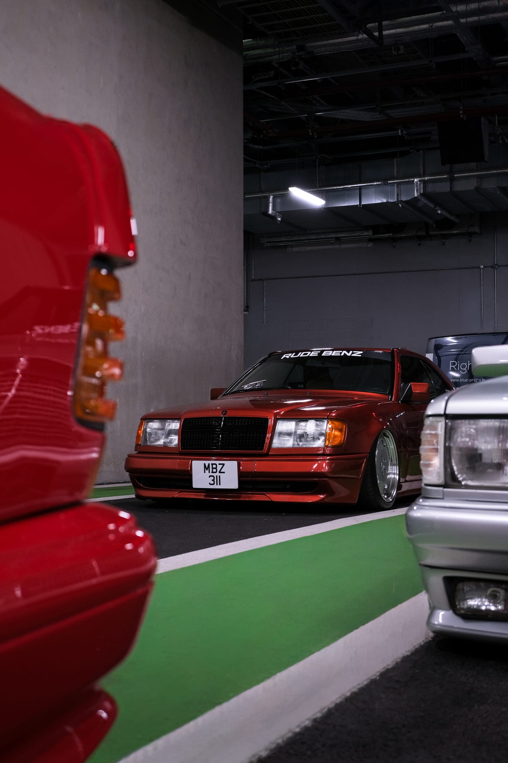 Modified red Mercedes W124 parked in an underground car park